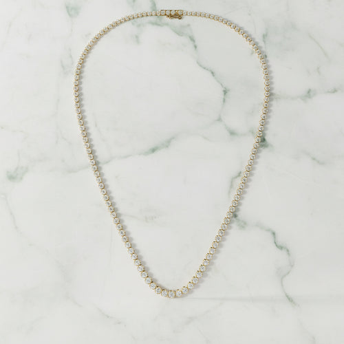 Gold necklace with small round stones on a light beige background