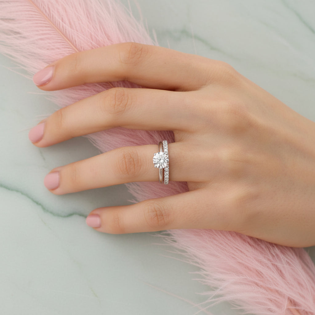 Hand wearing a silver ring with a diamond on a pink textured background