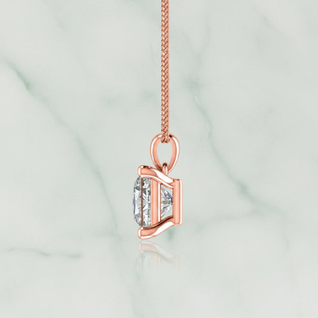 Rose gold pendant with a clear gemstone on a white background
