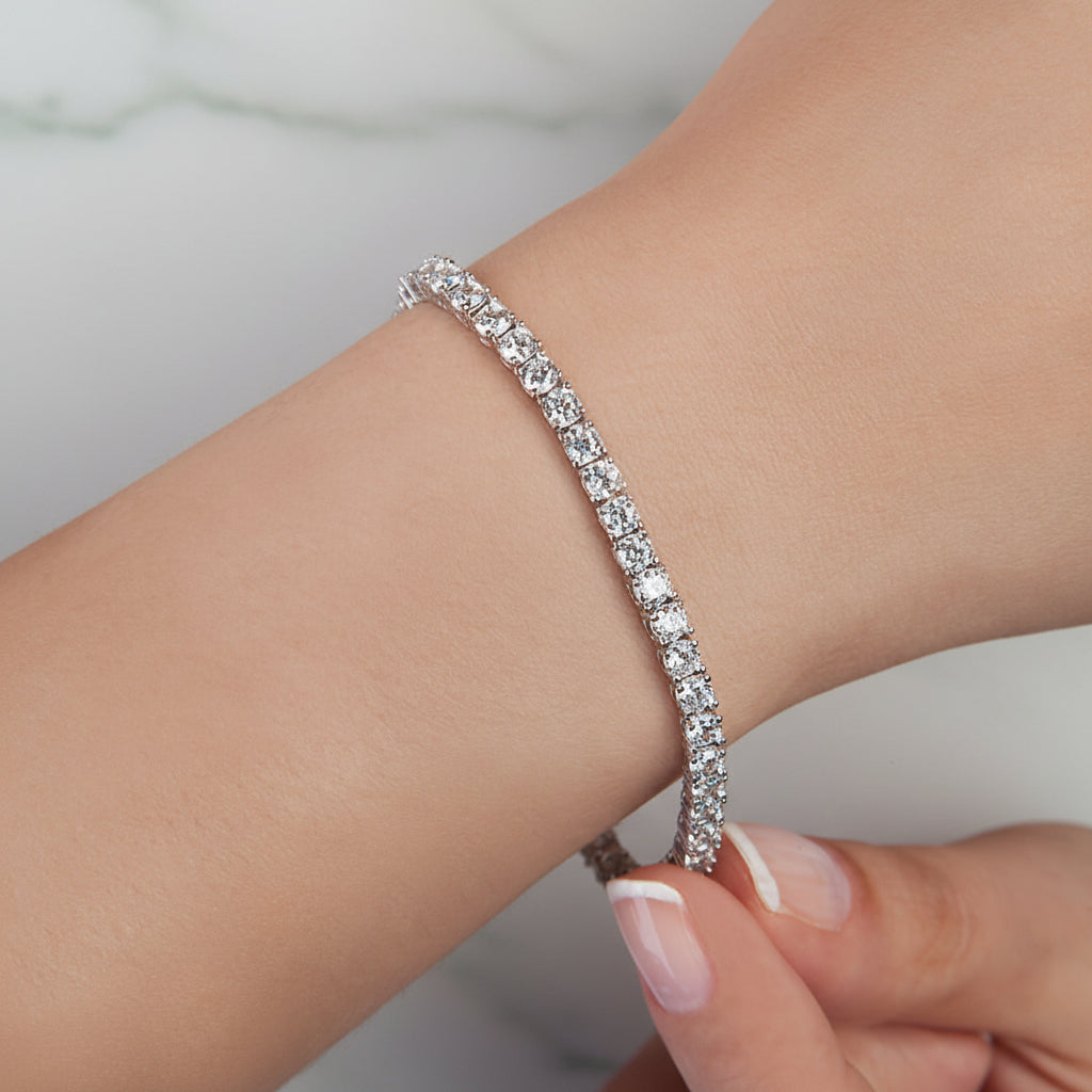 Silver bracelet with clear stones on a wrist against a soft pink background