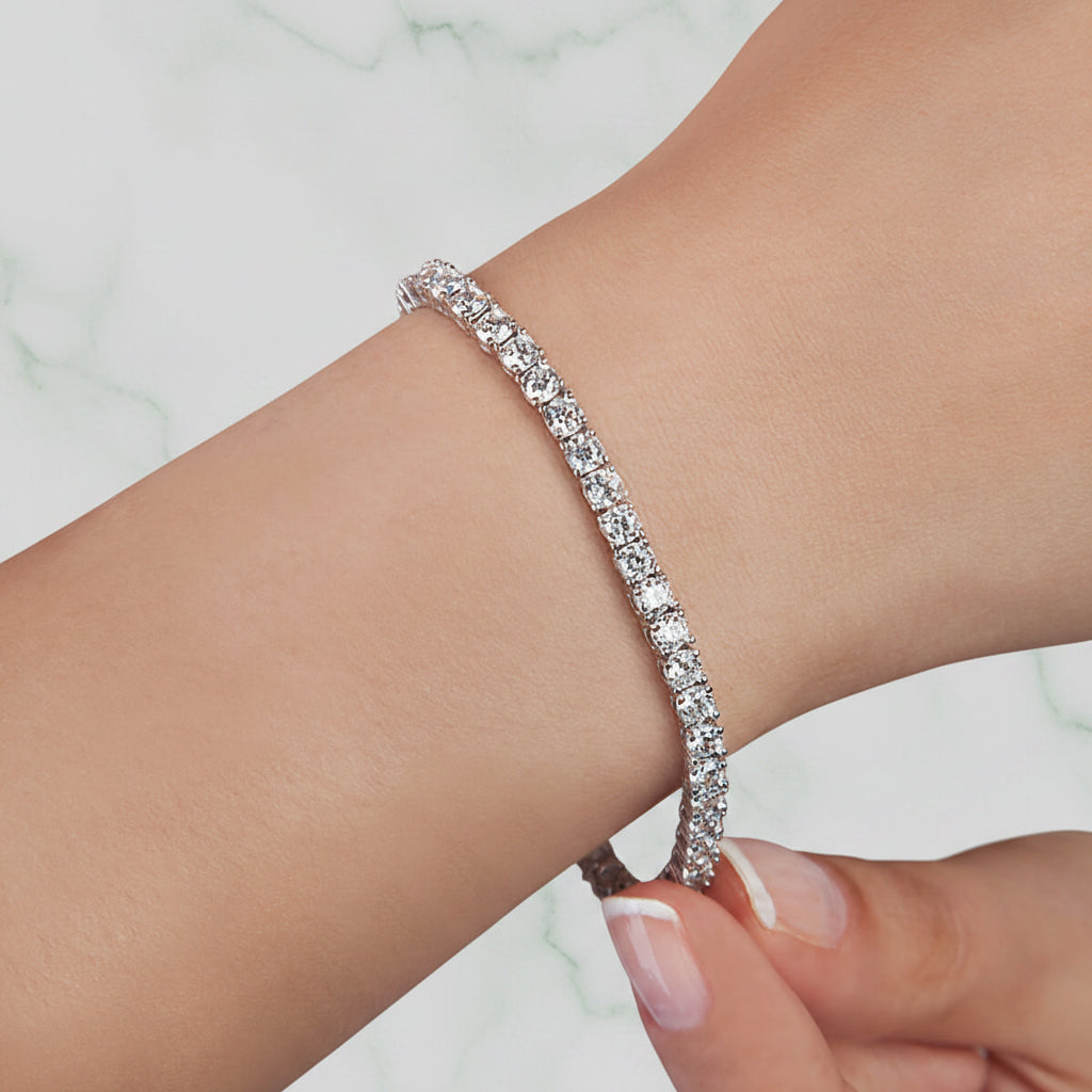 Silver bracelet with clear stones on a wrist against a soft pink background